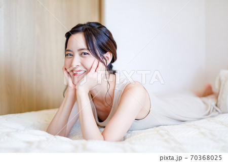 ベッドで頬杖を突いて横たわる女性 ベッドで頬杖を突いて横たわる女性 70368025