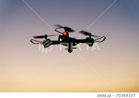 Toy drone quad copter against sunset sky 70369107