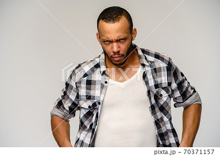 Photo of emotional angry sad young african-american man standing over light grey background 70371157