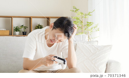 リビングでテレビゲームをする男性 リビングでテレビゲームをする男性 70371346