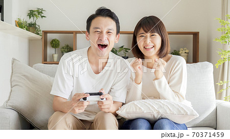 リビングでテレビゲームをするカップル 夫婦の写真素材