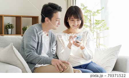 スマホを操作する夫婦・カップル スマホを操作する夫婦・カップル 70371522