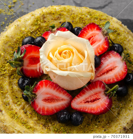 Pistachio cheesecake with berries and rose 70371931