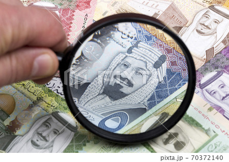 Saudi riyal in a magnifying glass a business background Saudi riyal in a magnifying glass a business background 70372140