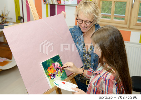 young teen girl painting with her teacher 70375596