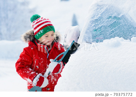 Child brushing off car. Kid with winter snow brush 70375772