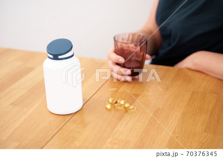 Caucasian woman takes supplements in the morning. Vitamins, pills, self care routine 70376345