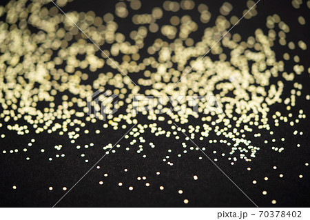 Beautiful Christmas light background. Abstract glitter bokeh and scattered sparkles in gold, on black 70378402
