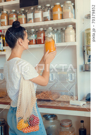 Young woman shopping in zero waste plastic free store with reusable mesh bag. Low waste lifestyle. Sustainable eco lifestyle 70379852