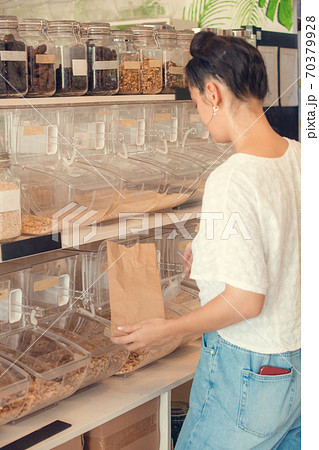 Young woman shopping in zero waste plastic free store with reusable mesh bag. Low waste lifestyle. Sustainable eco lifestyle Young woman shopping in zero waste plastic free store with reusable mesh bag. Low waste lifestyle. Sustainable eco lifestyle 70379928