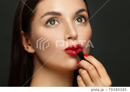Dreamy woman face with red glossy lips and lipstick on black background Dreamy woman face with red glossy lips and lipstick on black background 70380385