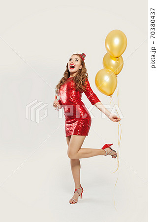 Happy surprised woman with yellow balloons standing on white background Happy surprised woman with yellow balloons standing on white background 70380437