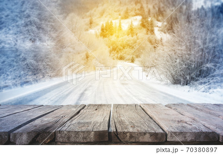 Wooden planks with winter mountain road in background Wooden planks with winter mountain road in background 70380897