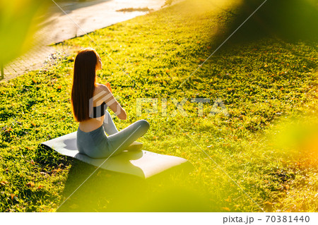 High-angle shot of calmly red-haired young woman meditating in lotus pose holding hands on knee 70381440