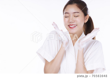 Adorable young woman washing her face with foam soap in hand while standing over isolated Adorable young woman washing her face with foam soap in hand while standing over isolated 70381648