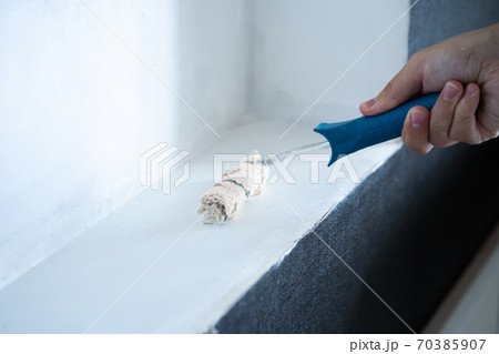 Renovation in the house. Painting a white wall with a roller with white paint. Rolling paint with a hand roller. Updating the paint on the wall Renovation in the house. Painting a white wall with a roller with white paint. Rolling paint with a hand roller. Updating the paint on the wall 70385907