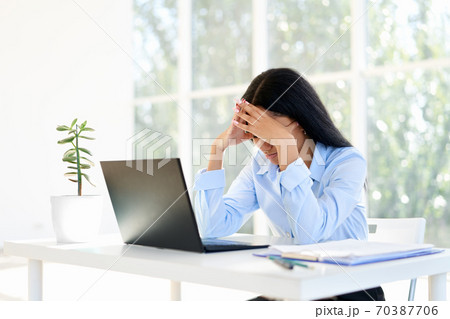 Stressed tired businesswoman closed face by two hands sitting in modern office Stressed tired businesswoman closed face by two hands sitting in modern office 70387706