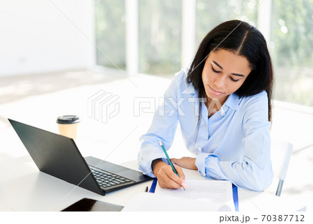 African american businesswoman with laptop and papers working at office African american businesswoman with laptop and papers working at office 70387712