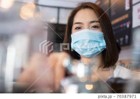 Asian barista women wearing face masks to prevent contagious diseases and serve customers in the coffee shop. The concept of prevention from COVID 19 Asian barista women wearing face masks to prevent contagious diseases and serve customers in the coffee shop. The concept of prevention from COVID 19 70387971
