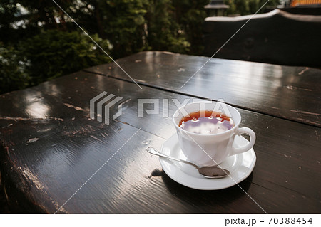 Cup with black tea onwooden background. White ceramic cup, place for text. 70388454