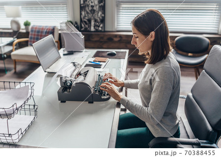 Young woman writing with an old typewriter 70388455