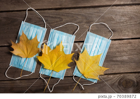 .Autumn fallen leaves and medical masks on wooden background. .Autumn fallen leaves and medical masks on wooden background. 70389872