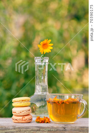 Macaroons cakes of different color, calendula flower with a stem 70390175