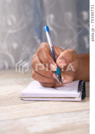 Close up of man hand writing on notepad. Close up of man hand writing on notepad. 70390731