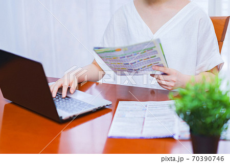 パンフを見ながら旅行の手配をする若い女性【goto travel キャンペーン】 70390746