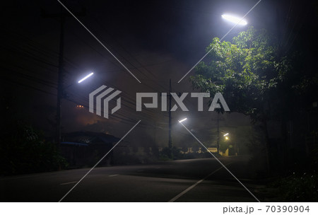 Empty road underneath street light at night with UFO on back 70390904