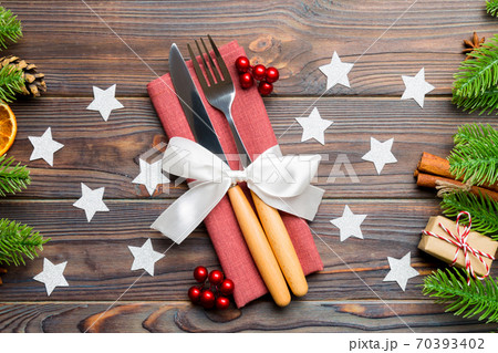 Top view of utensils on festive napkin on wooden background. Christmas decorations with dried fruits and cinnamon. Close up of New year dinner concept 70393402
