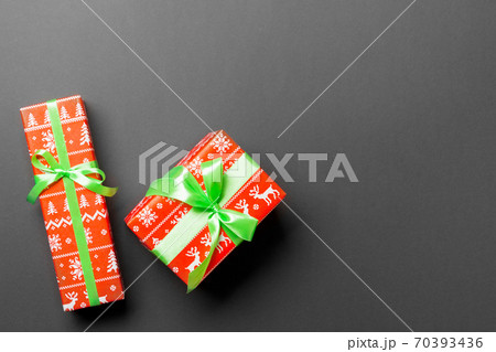 wrapped Christmas or other holiday handmade present in paper with green ribbon on black background. Present box, decoration of gift on colored table, top view wrapped Christmas or other holiday handmade present in paper with green ribbon on black background. Present box, decoration of gift on colored table, top view 70393436