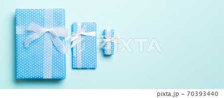 wrapped Christmas or other holiday handmade present in paper with white ribbon on blue background. Present box, decoration of gift on colored table, top view 70393440