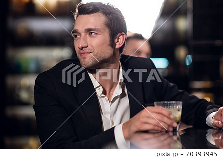 a handsome man in a shirt and jacket with a cocktail in his hands in a bar, portrait, close-up 70393945
