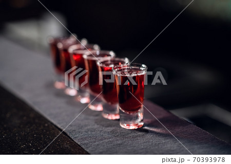 a row of shots with red liquor on the bar on the fabric close up 70393978