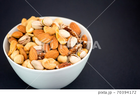Hazelnut ,Pecan nut, Pistachio nut ,Peanuts nut,Almond nut mixed salt in a wooden plate is Protein food and healthy food for diet food on a black background. 70394172