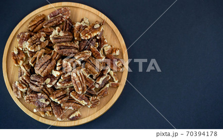 pecan nut or Pekannuss nuts group Protein and healthy food for diet in a wooden plate on a black background. 70394178
