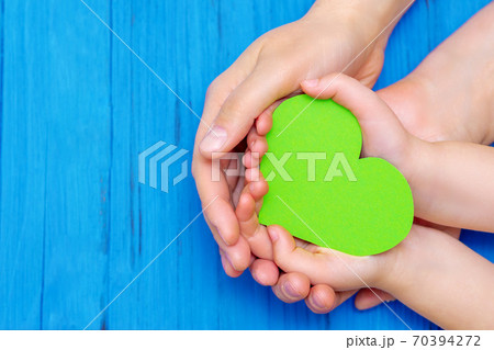 Green heart in hands of adult and child. Green heart in hands of adult and child. 70394272