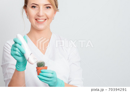 Woman shaves green cactus. 70394291