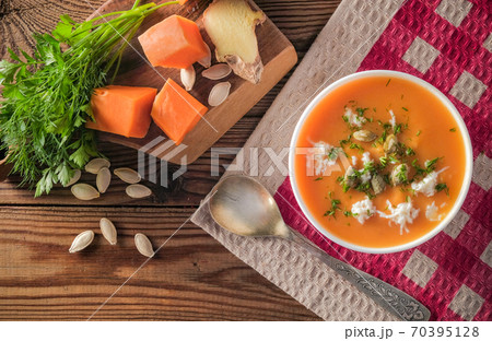 Pumpkin cream soup with cheese and seeds on a wooden table on a red Pumpkin cream soup with cheese and seeds on a wooden table on a red 70395128