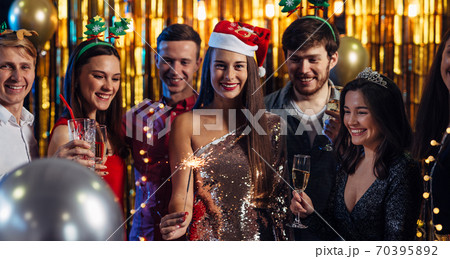 Group of friends celebrating with fireworks and glasses enjoying Christmas party Group of friends celebrating with fireworks and glasses enjoying Christmas party 70395892