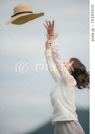 草原で帽子で戯れる女性 70395930