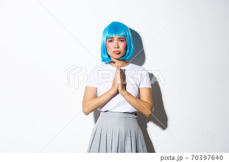 Portrait of sad asian girl in blue wig, begging for help, looking desperate at camera, standing over white background Portrait of sad asian girl in blue wig, begging for help, looking desperate at camera, standing over white background 70397640