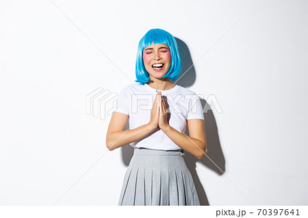 Portrait of silly asian girl in blue wig begging for help, pleading while standing over white background Portrait of silly asian girl in blue wig begging for help, pleading while standing over white background 70397641