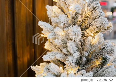 artificial green fir tree under snow with garland  70398152