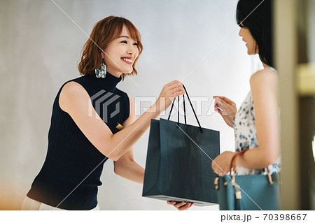 商品を手渡す女性の店員 70398667