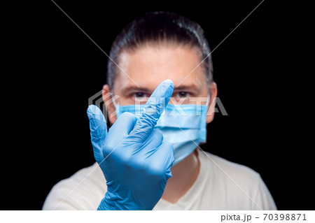hand in glove showing obscene gesture middle finger male portrait of a doctor in a medical mask, closeup isolated on black background. 70398871