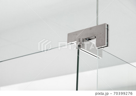 glass door hinges to bathroom, close up of hinged accessories of transparent partitions on the white wall with copy space. glass door hinges to bathroom, close up of hinged accessories of transparent partitions on the white wall with copy space. 70399276