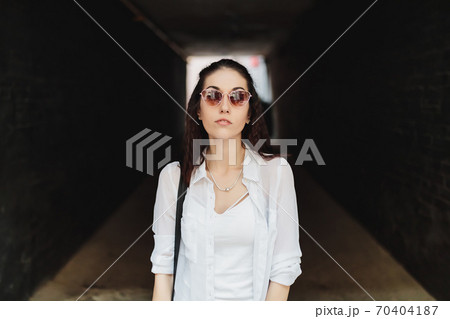 Woman in sunglasses in a dark hallway. Woman in sunglasses in a dark hallway. 70404187