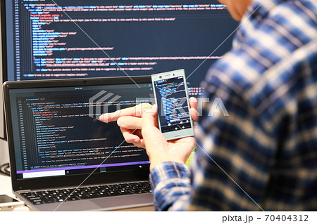 エンジニア_プログラミング開発イメージ_スマホを持ちノートPCを指さす エンジニア_プログラミング開発イメージ_スマホを持ちノートPCを指さす 70404312